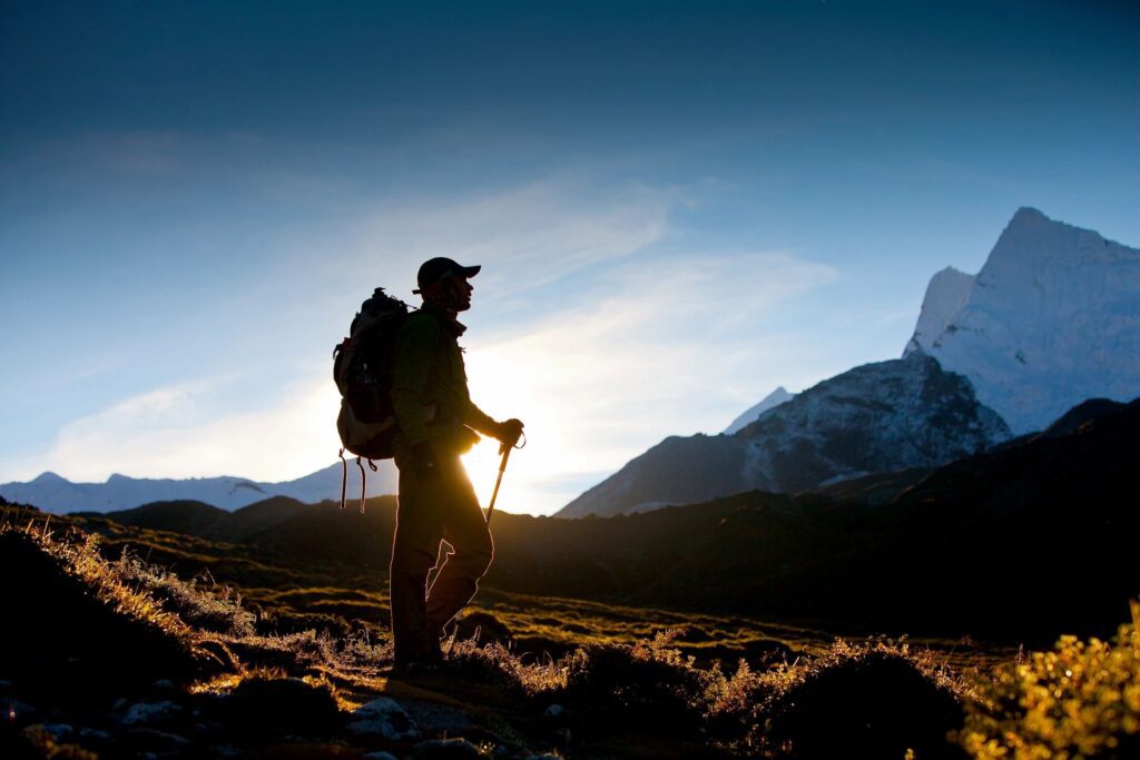 A man with a backpack and hiking poles on the side of a mountain.
